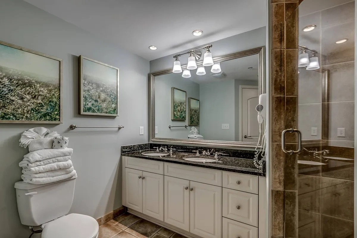 A bright and organized bathroom with a double sink vanity, large mirror, and tasteful artwork. The space feels serene and functional—ideal for both morning routines and unwinding at night.