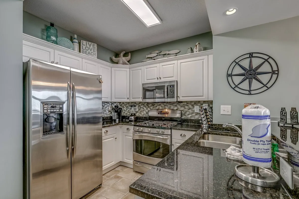 A cheerful kitchen scene highlighting stainless steel appliances, polished granite countertops, and decorative nautical accents. The layout offers plenty of space for collaborative cooking or entertaining guests, emphasizing functionality and style.