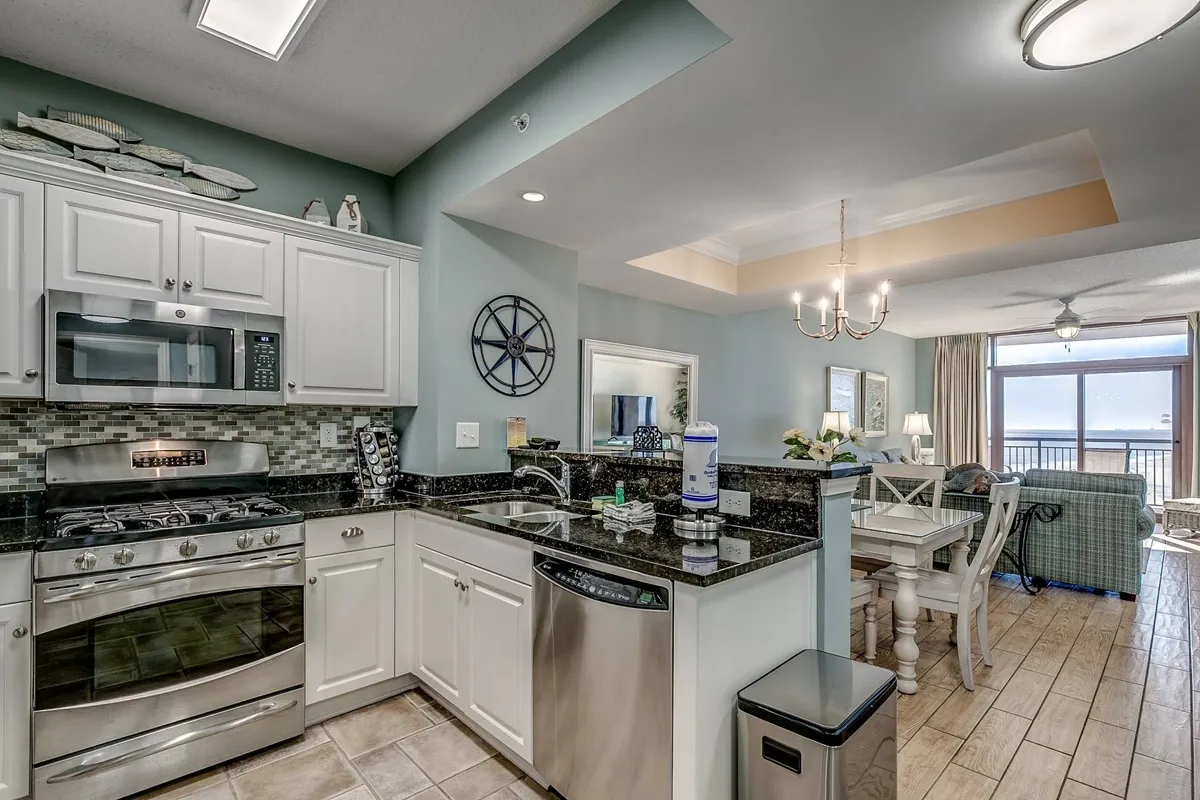 A modern, inviting kitchen featuring sleek appliances, granite countertops, and a spacious dining area with a view. Nautical decor elements add a touch of coastal charm, and the open layout creates a welcoming space for both cooking and gathering.